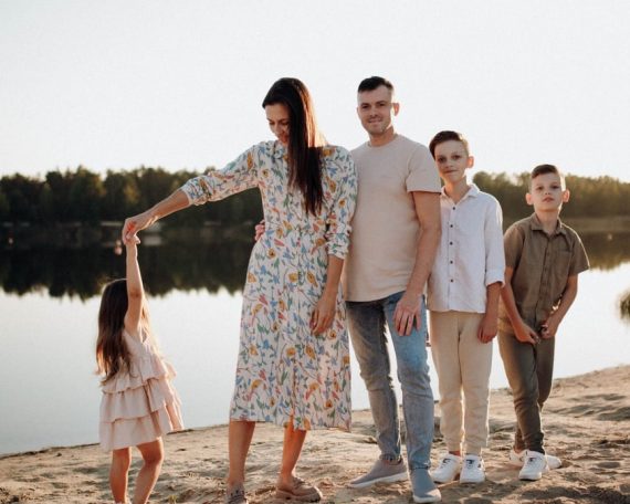 A family of five enjoys a serene lakeside vacation at sunset, capturing precious moments together.
