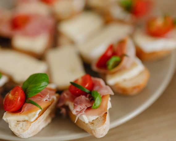 Delicious bruschetta appetizers with prosciutto, cheese, and cherry tomatoes on a serving platter.